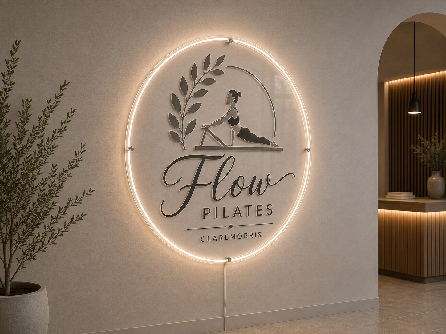 Clear acrylic Pilates studio sign with grey raised lettering and warm white LED border lighting.